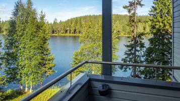 A balcony with a metal railing overlooking a lake surrounded by trees.