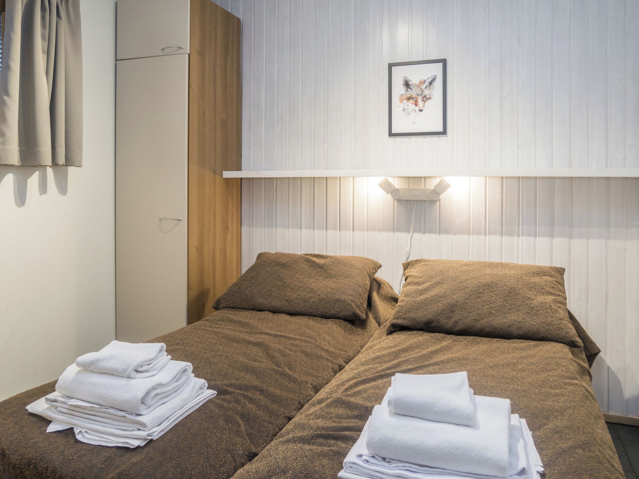 A double bed with a headboard, two pillows, and a bedside table with a lamp.
