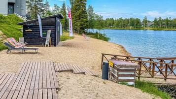 A lakeside wooden deck with lounge chairs, a small wooden structure, and a dock extending into the water.