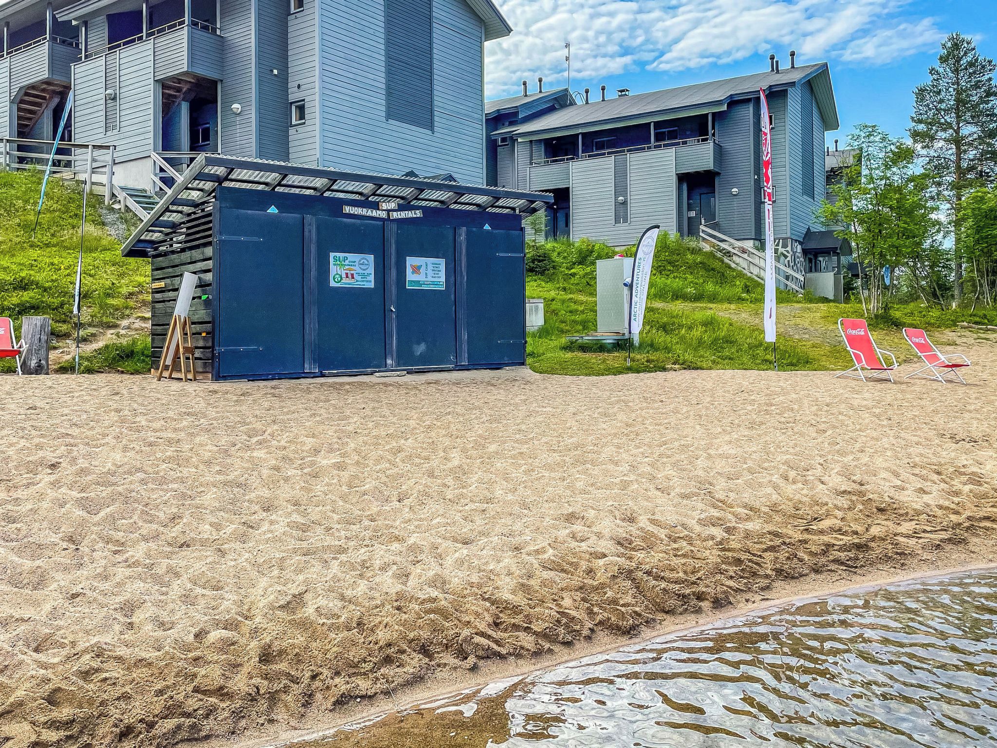 A beachside hotel with a small building, outdoor seating, and a clear sky.