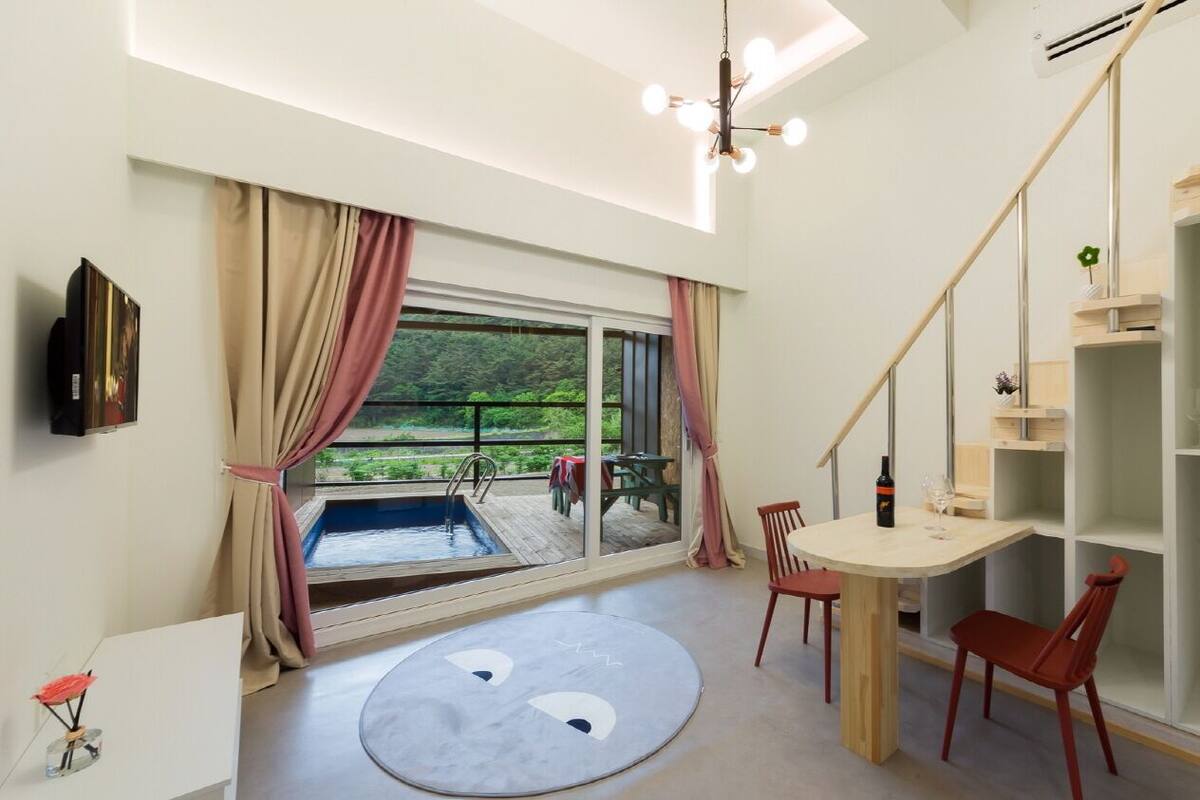 Une chambre moderne dotée d’une grande fenêtre, d’une piscine, d’un coin repas et d’une bibliothèque intégrée.