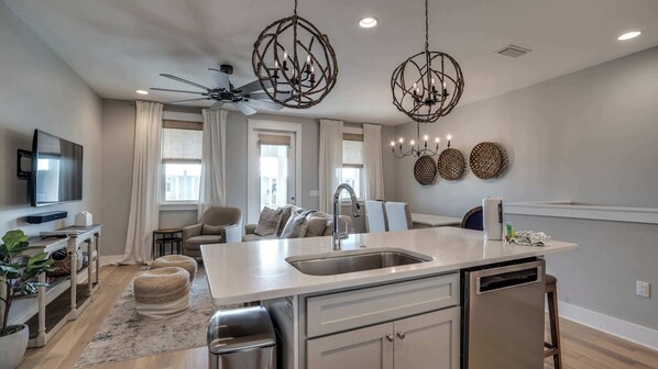A modern kitchen with a central island, a ceiling fan, and a dining area with a table and chairs.