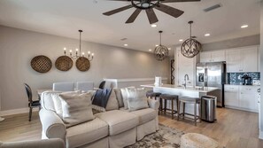 A modern kitchen with a central island, stainless steel appliances, and a ceiling fan. - Golf Cart Included! Walk or Bike to Beach & Pool! ~ Crew Rest at 30A Townhomes on 30A (Santa Rosa Beach)