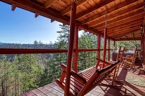 A wooden deck with benches overlooking a forested landscape.