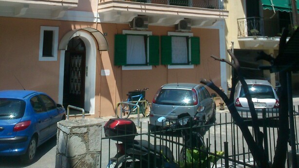 Un immeuble résidentiel à plusieurs étages, doté de balcons, d’une entrée sécurisée et de voitures garées.
