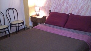 Une chambre à coucher avec un lit, deux chaises, une table de chevet avec une lampe et un mur à texture.