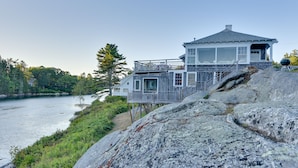 Une maison située sur la côte, dotée d’une terrasse en bois et offrant une vue sur l’eau.