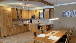 Una cocina moderna con armarios de madera, una mesa de comedor con sillas azules y un microondas.