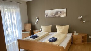 Un dormitorio moderno con una cama grande, dos mesitas de noche, una silla y un cuadro en la pared.