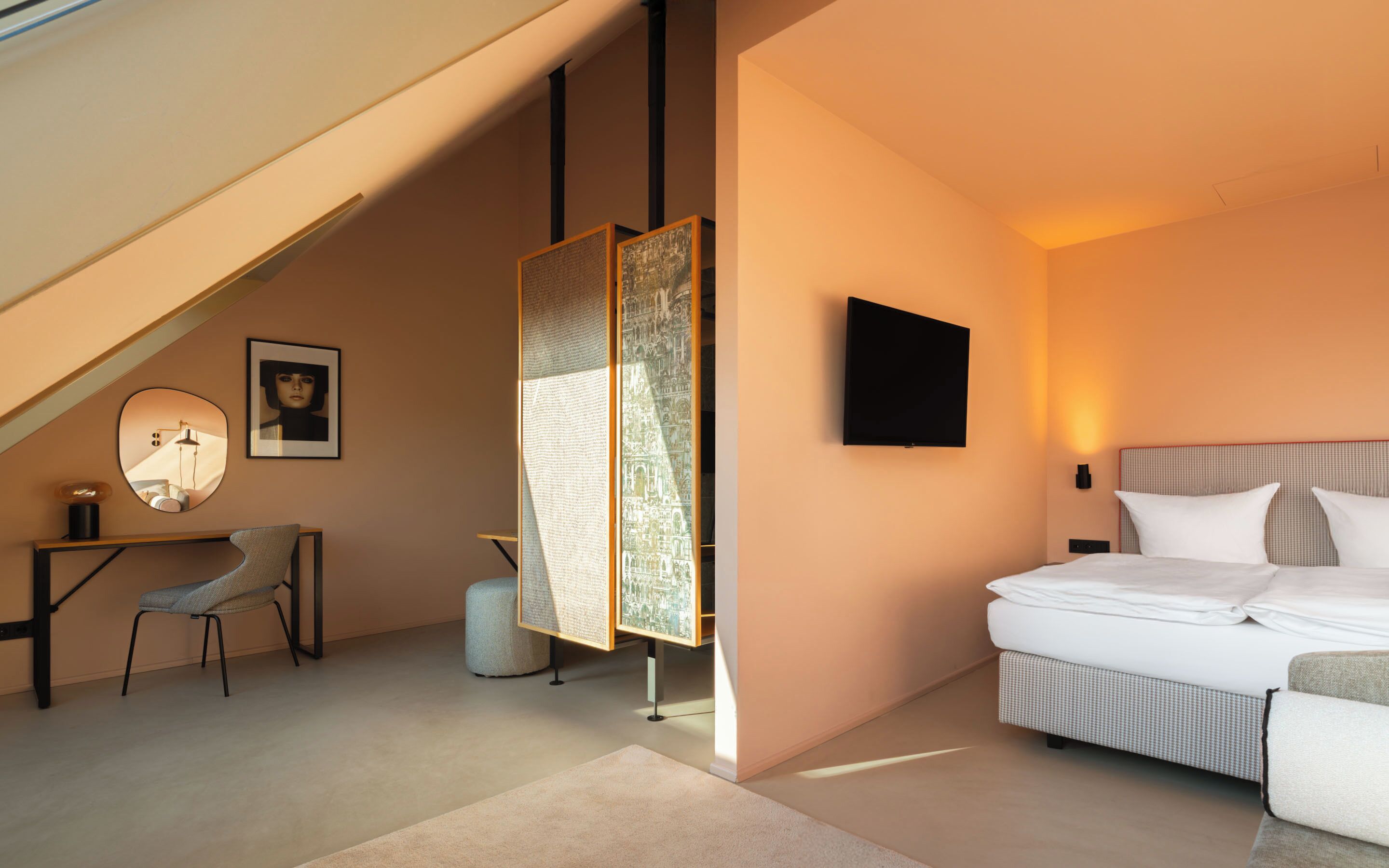 A modern bedroom with a bed, a desk, a chair, and a large window.