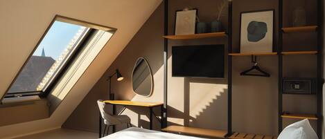 Un dormitorio moderno con tragaluz, un escritorio, una cama y estanterías empotradas.