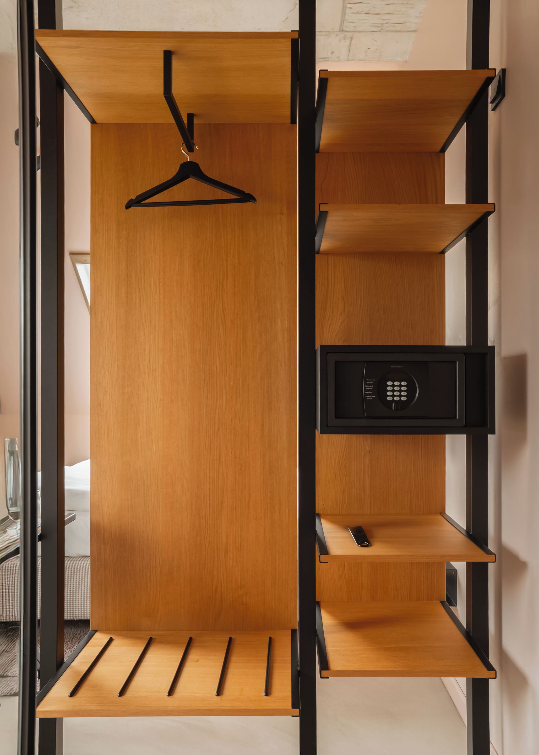 A modern closet with wooden shelves and a black hanging rack.