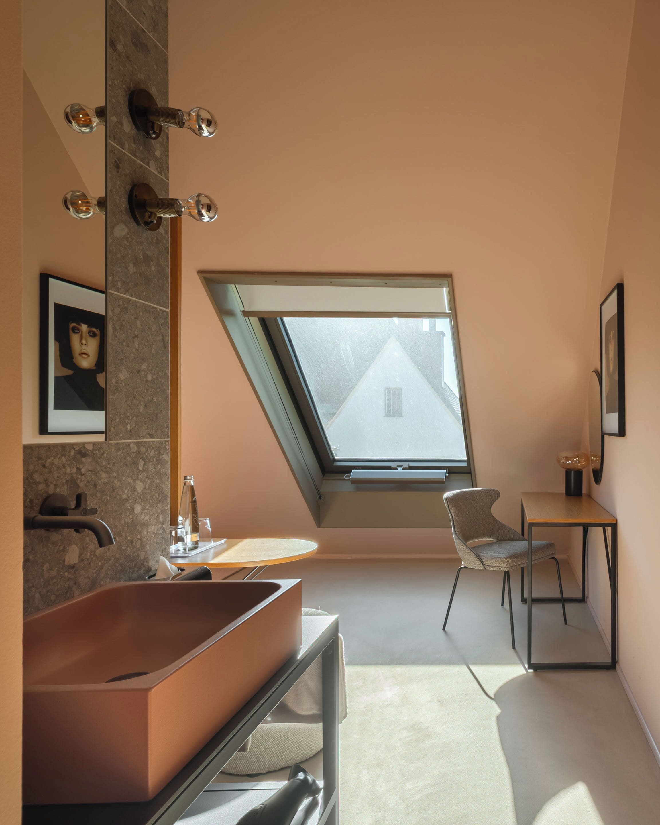 Un baño moderno con un tragaluz grande, una bañera y una pequeña mesa con una silla.