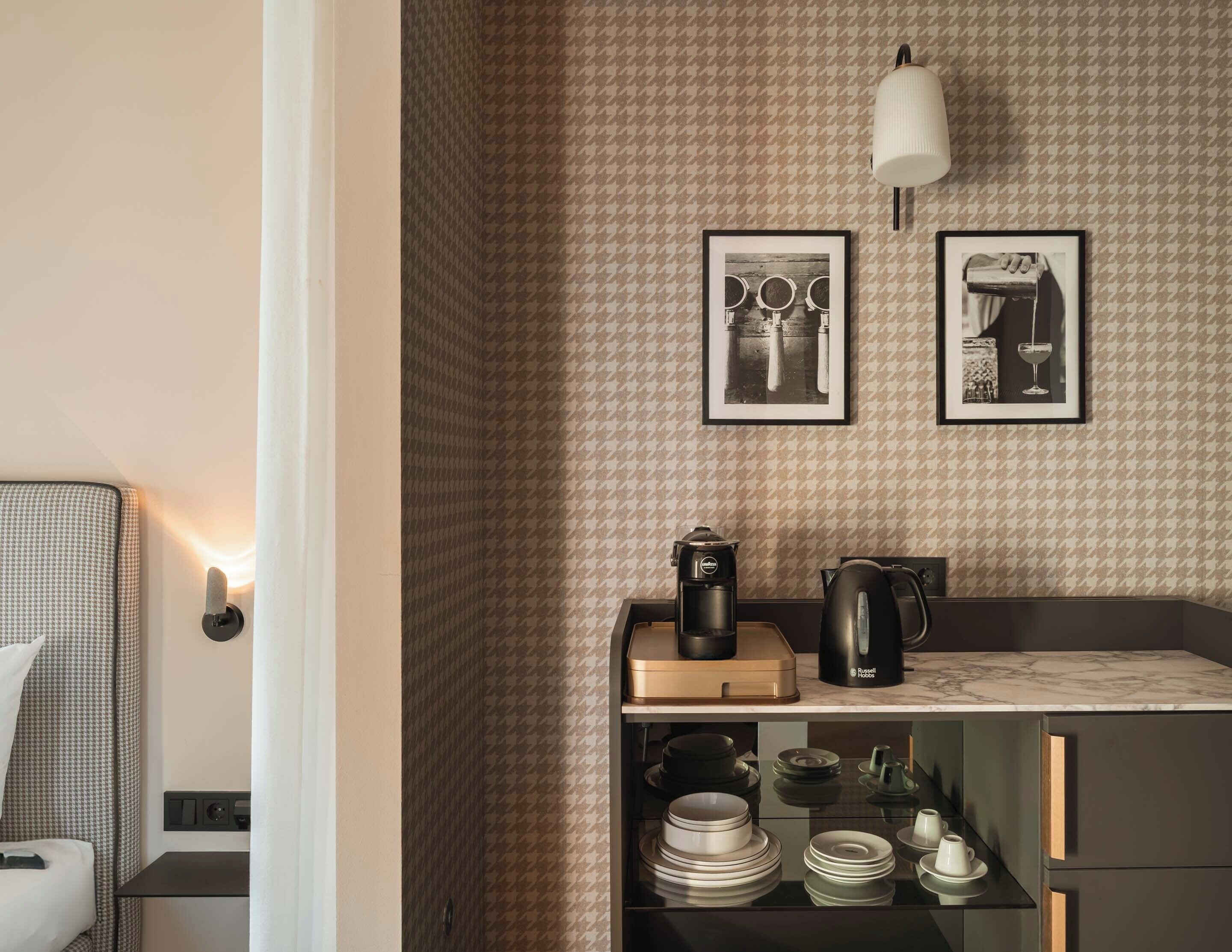 A compact kitchen with a houndstooth-patterned backsplash, a coffee maker, and a kettle on the countertop.