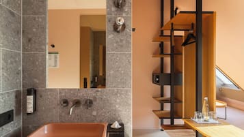 A modern bathroom with a large sink, a mirror, and a wooden shelf unit.
