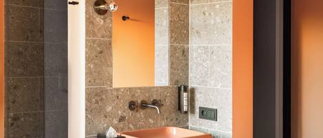 Un baño moderno con un lavamanos rectangular, un espejo grande y un perchero para toallas.