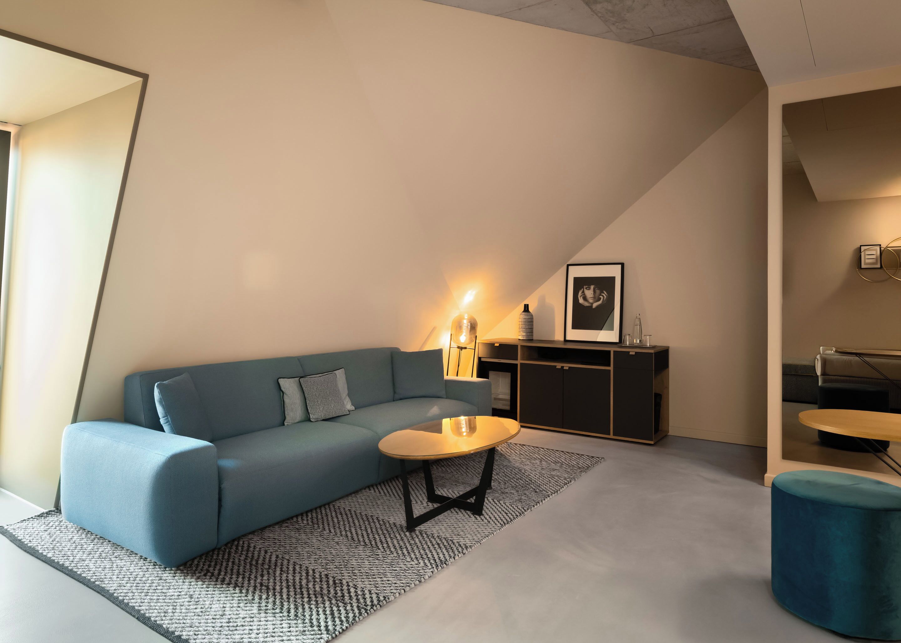 Una sala de estar moderna con un sofá azul, una mesita redonda y un aparador.