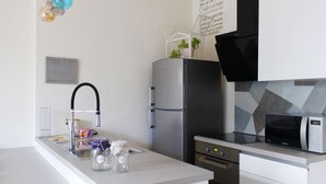 Una cocina moderna con un refrigerador de acero inoxidable, un microondas y un lavamanos con grifo.