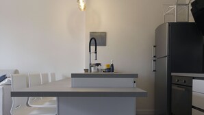 Una cocina compacta con una isla integrada, un fregadero y un refrigerador.