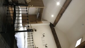 A high-ceilinged room with a bed, a wooden beam structure, and a staircase. - Nuneaton - Cottage - Sleeps 2 - Parking - Garden (Nuneaton)