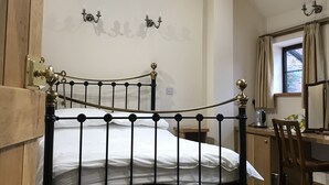 A bedroom with a black metal bed frame, a wooden door, a desk with a chair, and a window with curtains. - Nuneaton - Cottage - Sleeps 2 - Parking - Garden (Nuneaton)