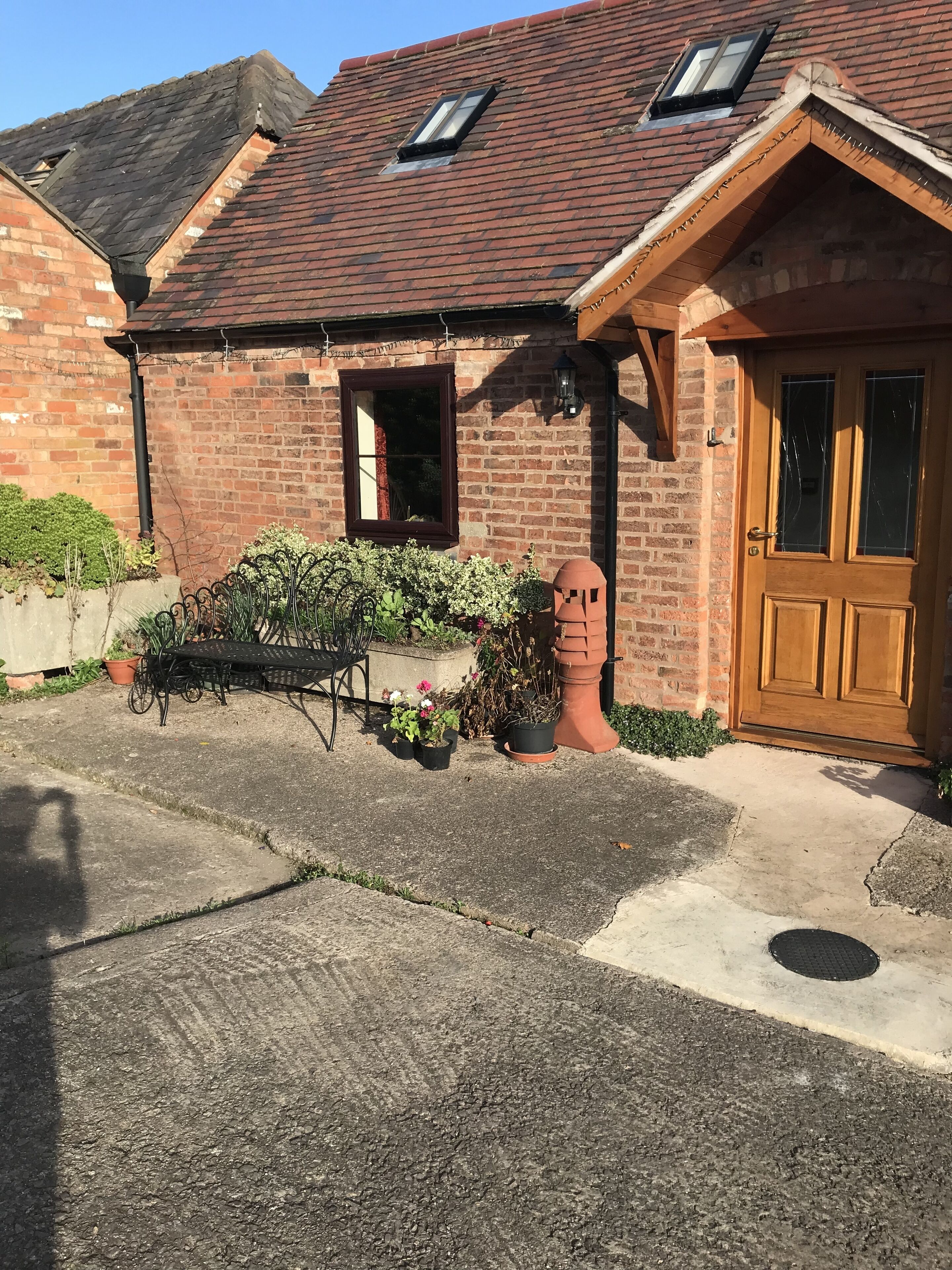 A brick house with a red-tiled roof, a wooden door, and a small window.