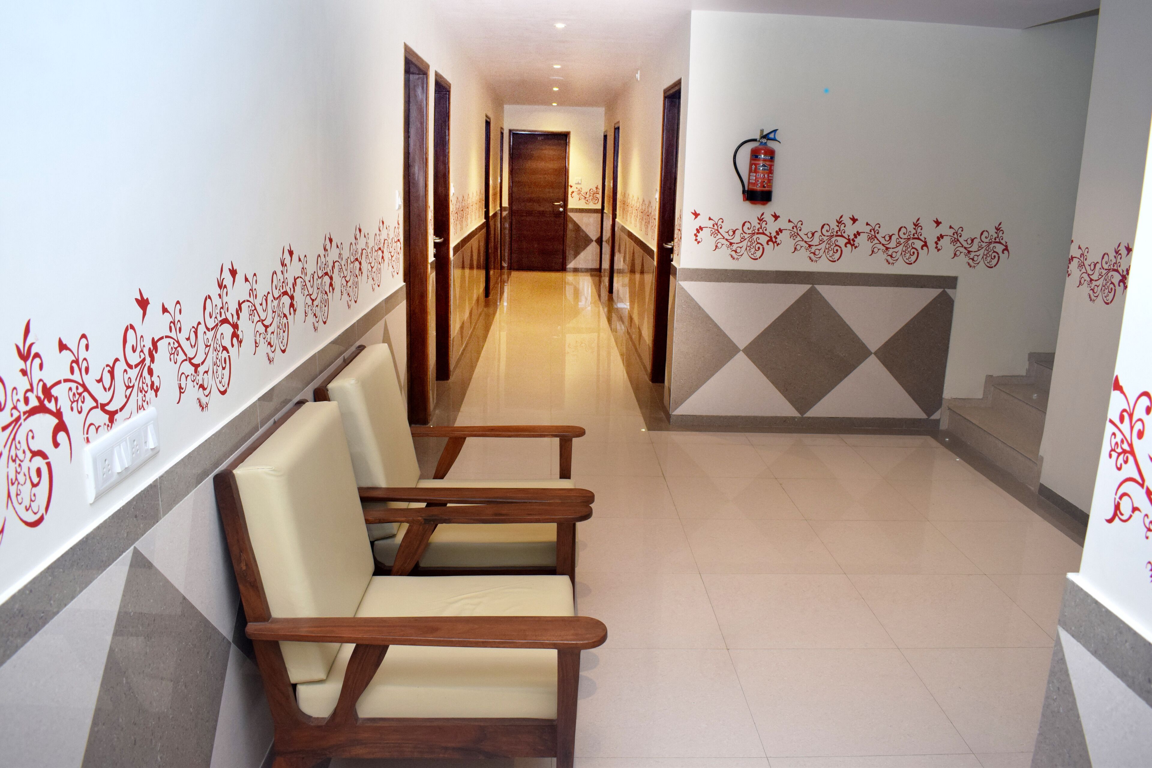 A hotel hallway with a wooden bench, a fire extinguisher on the wall, and a patterned wall design.