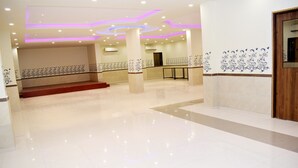 Eine großzügige Lobby mit Marmorboden, einer mit rotem Teppich ausgelegten Treppe und dekorativen Wandmustern.