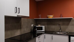 A kitchen with white cabinets, a black countertop, a microwave, a coffee maker, and a sink.