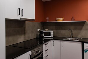 A kitchen with white cabinets, a black countertop, a microwave, a coffee maker, and a sink.