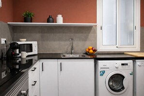 Cocina compacta con microondas, cafetera, lavabo y lavadora.