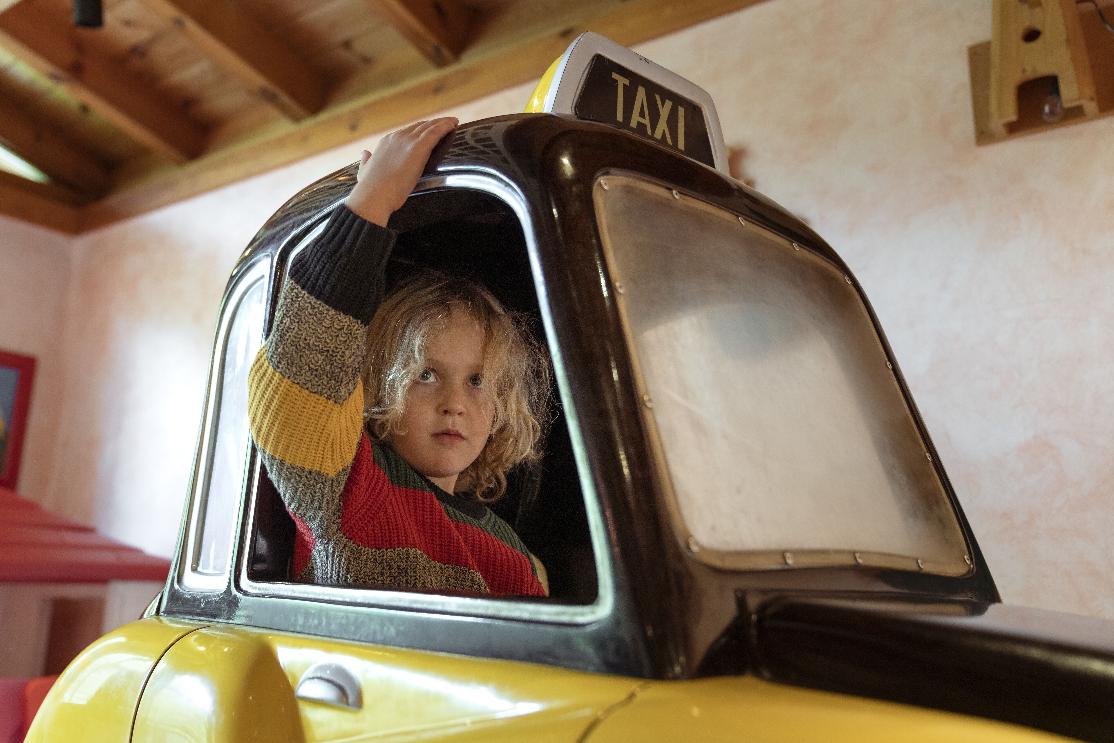 Niño dentro de un taxi amarillo con la señal 'TAXI' en la parte superior.
