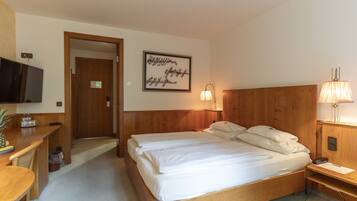 Ein Hotelzimmer mit einem hölzernen Bett, einem Schreibtisch mit Fernseher, einer Wandlampe und einem gerahmten Zitat an der Wand.