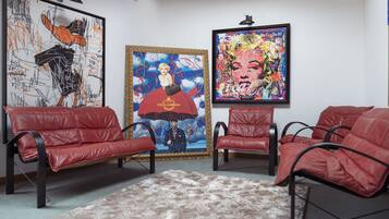 A room with red leather sofas, a patterned rug, and three framed artworks on the wall.