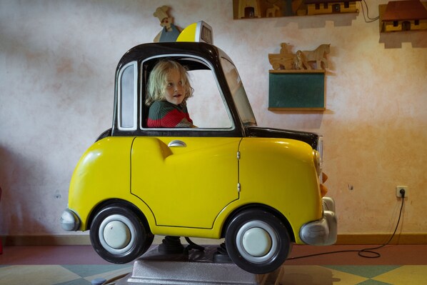 A yellow toy car with a child inside, placed on a stand.