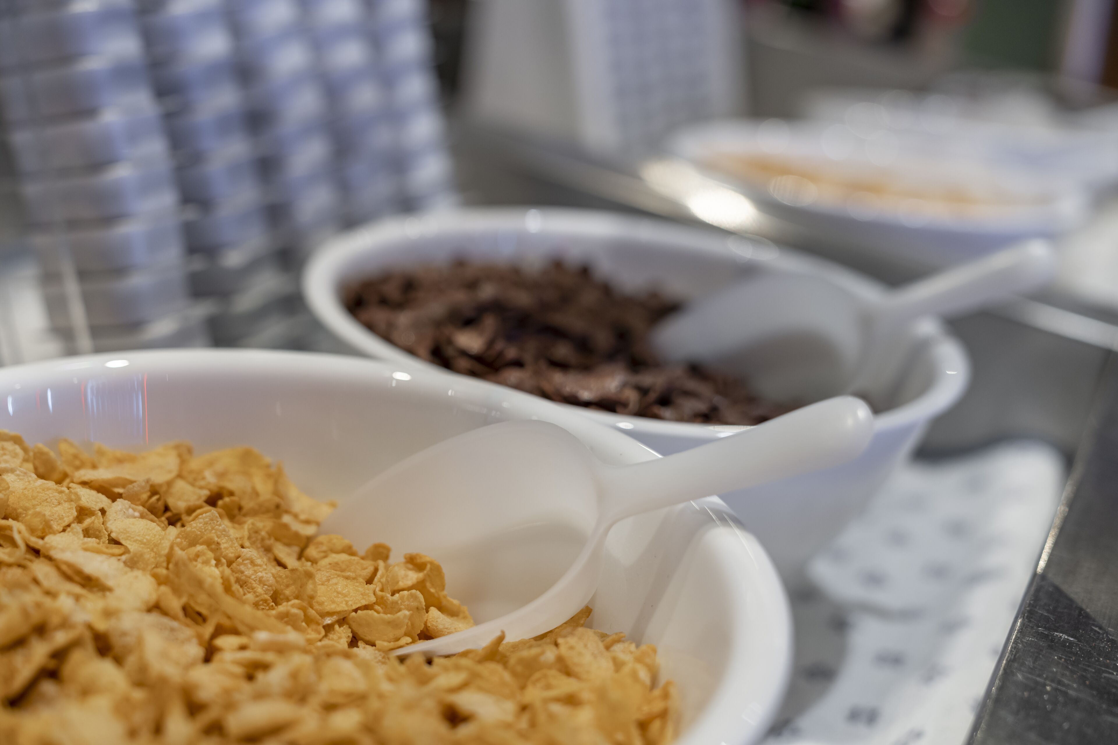 Primer plano de tazones de cereal con una cuchara, un bol de chispas de chocolate y un bol de hojuelas de cereales.