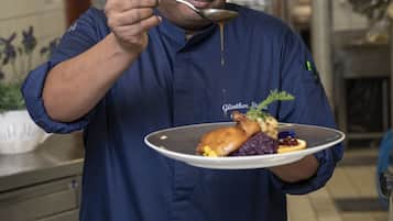 A person in a blue shirt holding a plate with food and a spoon.