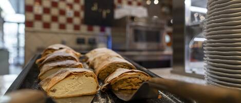 Mostrador de pastelería con bollería y una pared a cuadros al fondo.