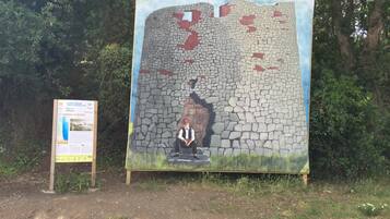 A large outdoor mural of a stone wall with a figure sitting in the foreground.