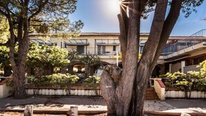 A courtyard with trees, a building with balconies, and a clear sky. - Hotel Oasis (Argelès-sur-Mer)