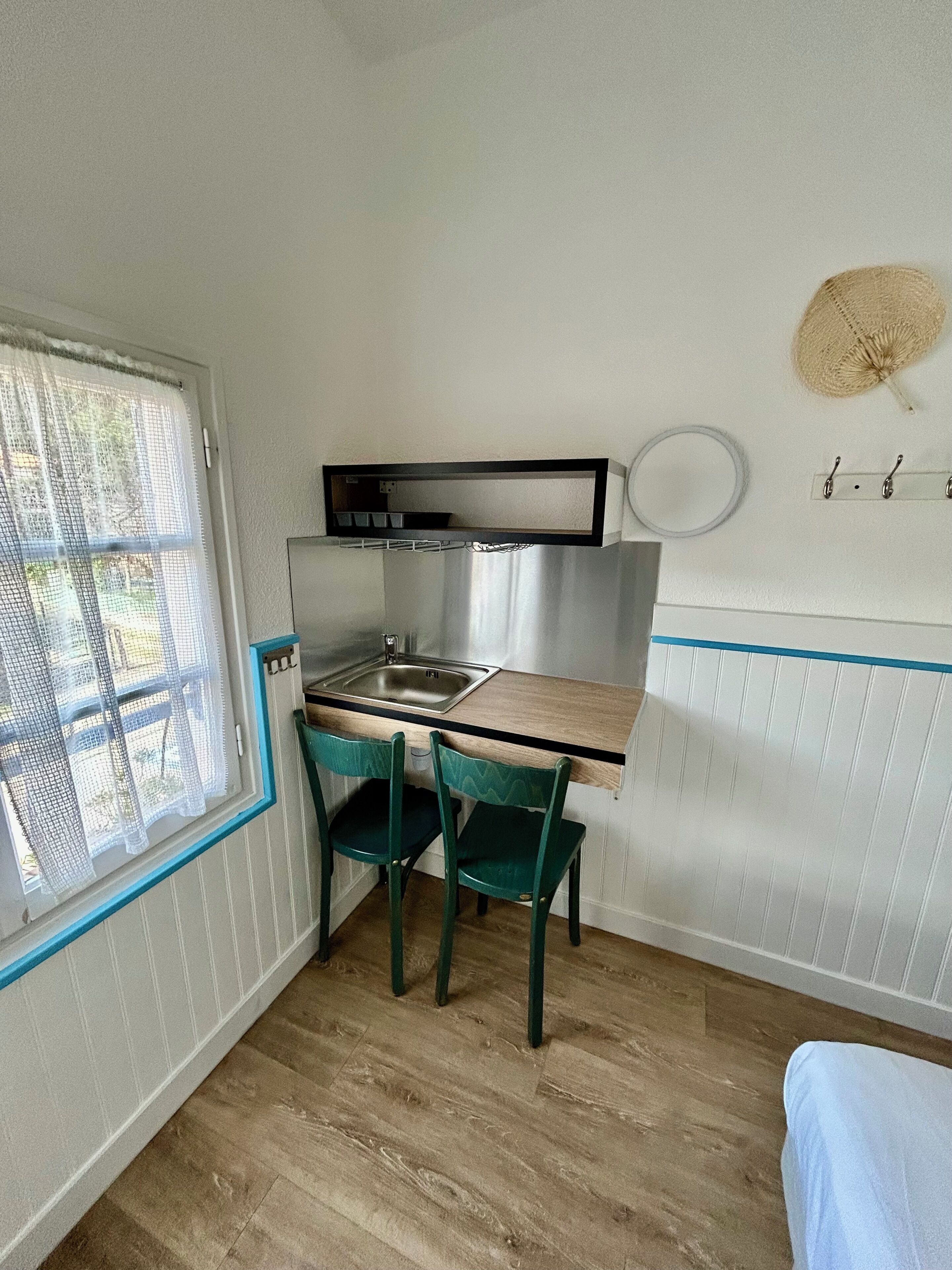 A compact kitchen with a sink, a small dining table, two chairs, and a window with a view.