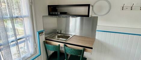 A compact kitchen with a sink, a small dining table, two chairs, and a window with a view.