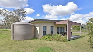 A modern house with a large water tank, a covered patio, and a well-maintained lawn.