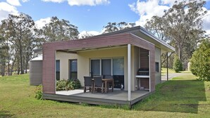 A modern single-story house with a patio, a dining area, and a barbecue setup.