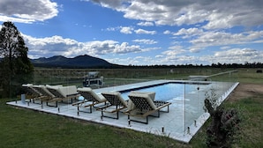 A swimming pool with lounge chairs and a view of mountains.