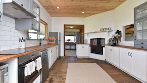 A modern kitchen with white cabinetry, stainless steel appliances, and a wooden ceiling.