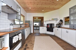 A modern kitchen with white cabinetry, stainless steel appliances, and a wooden ceiling.