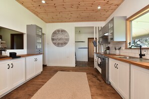 Une cuisine avec des meubles en bois, une grande horloge et une vue sur la salle à manger.