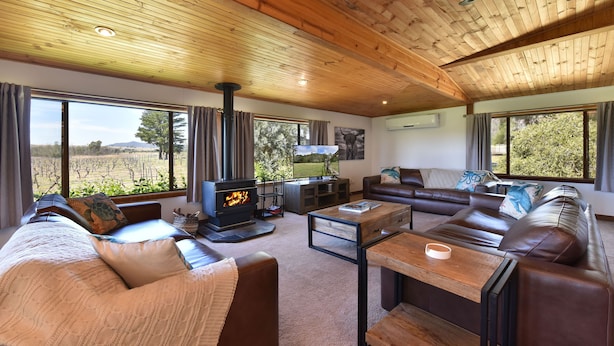 A cozy living room with a fireplace, leather sofas, and large windows offering a view of the outdoors.