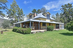 A two-story house with a covered porch, a chimney, and a large lawn.